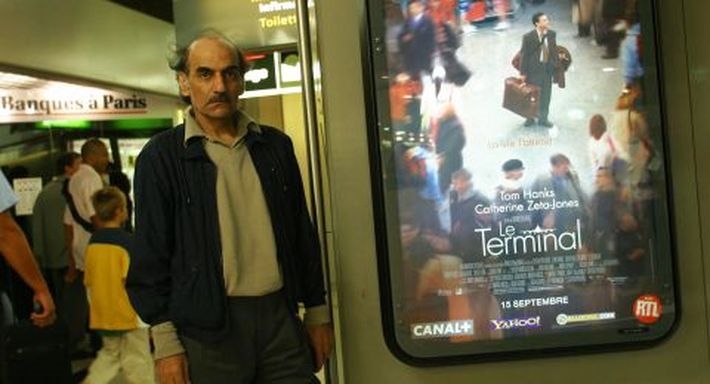 مهران كريمي ناصري بجوار دعاية فيلم The Terminal