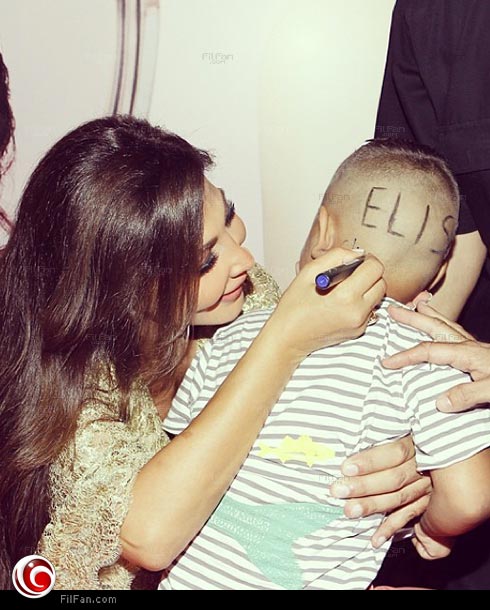 إليسا أثناء كتابتها لاسمها على رأس الطفل