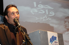 علي الحجار وفي الخلفية الملصق الدعائي لألبوم "حوا وآدم"