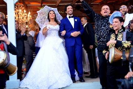 إيمي سمير غانم تمسك بمظلة في زفتها على حسن الرداد